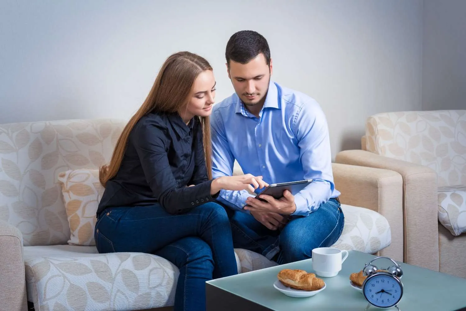 Couple on a sofa checking health plan details together on a tablet